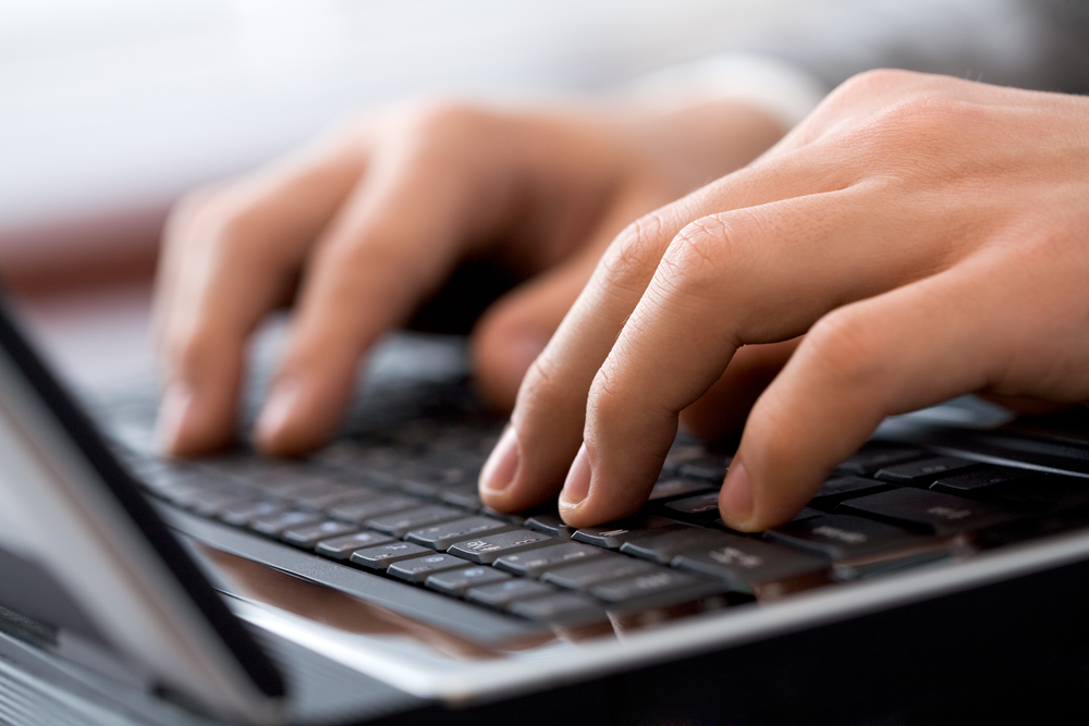 Close-up of male fingers typing a business document on the black laptop